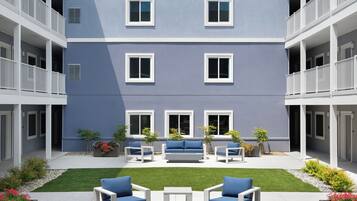 A multi-story building with balconies, a courtyard with seating, and a well-maintained lawn.