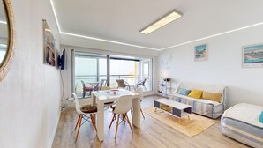 A modern living room with a dining area, large windows, and a balcony. - Atlantide Ouest - Getaway just a stone's throw from the ocean (Saint-Hilaire-de-Riez)