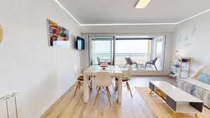 A modern living room with a dining area, large windows, and a view of the beach. - Atlantide Ouest - Getaway just a stone's throw from the ocean (Saint-Hilaire-de-Riez)