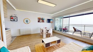 A modern living room with a dining area, a TV, and a balcony with chairs. - Atlantide Ouest - Getaway just a stone's throw from the ocean (Saint-Hilaire-de-Riez)