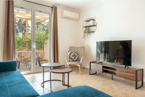 Una sala moderna con sofá, televisor y un sillón con cojín decorativo.