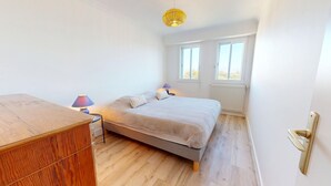 Een slaapkamer met een bed, twee bedlampen, een houten dressoir en een raam met uitzicht.