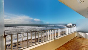Een balkon met uitzicht op zee, een houten vloer en een leuning.