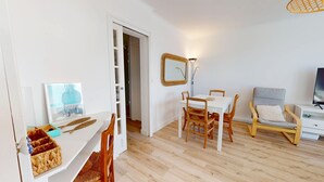 Een moderne woonkamer met een eethoek, een televisie en een spiegel.