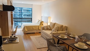 Una habitación de hotel moderna con cama, sofá, mesa de comedor y sillas.