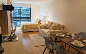 A modern hotel room with a bed, sofa, dining table, and chairs. - Luxury Loft | Panoramic View | Gym | Coworking (Bogotá)