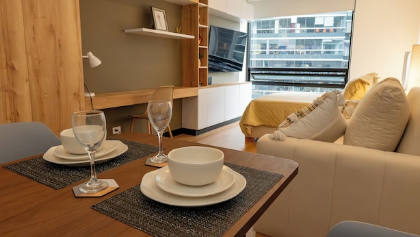Una sala de estar moderna con comedor, un sofá y una televisión.
