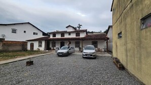 Un edificio de dos pisos con camino de grava y dos coches estacionados.