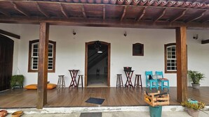 Un porche de madera con piso de baldosas, una mesa pequeña, dos sillas y una planta en maceta.