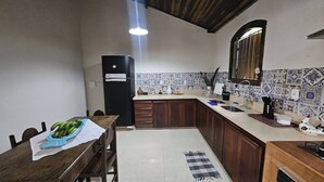 Una cocina con una mesa de madera, un refrigerador, un lavamanos y un salpicadero de azulejos.