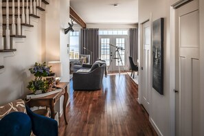 A spacious living area with a staircase, a sofa, a table with a lamp, and a telescope.