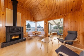L'intérieur d'un chalet en bois, avec une cheminée, des meubles en bois et de grandes fenêtres.