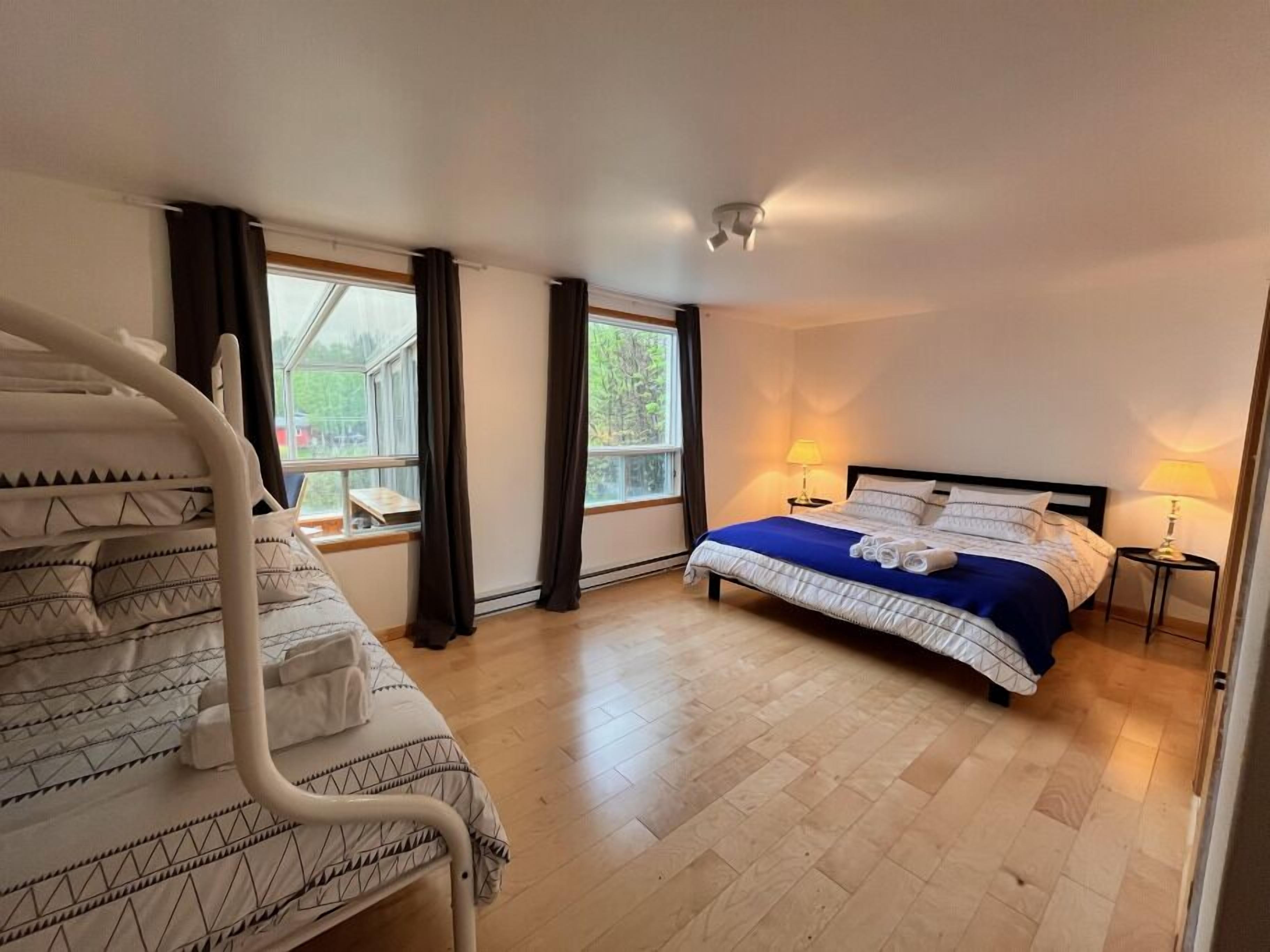 Une chambre à coucher avec un lit, une fenêtre, une table de chevet et une lampe.