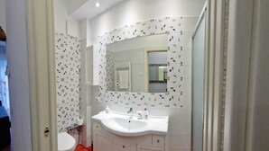 Baño con lavamanos, espejo y retrete blanco.