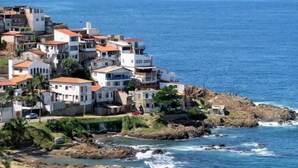 Un pueblo costero con edificios cerca del mar, costa rocosa y agua azul cristalina.