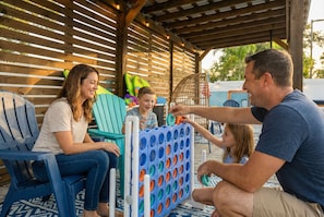 Un espace extérieur abrité, doté de lambris en bois, d’une chaise en plastique bleue et d’une structure de jeux pour enfants.
