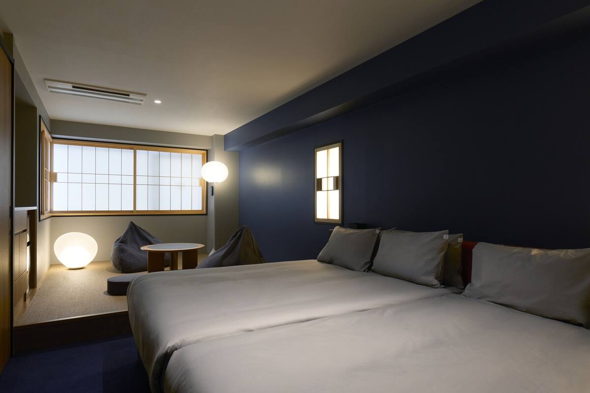 A hotel room with a bed, bedside table, lamp, and a window with a view.
