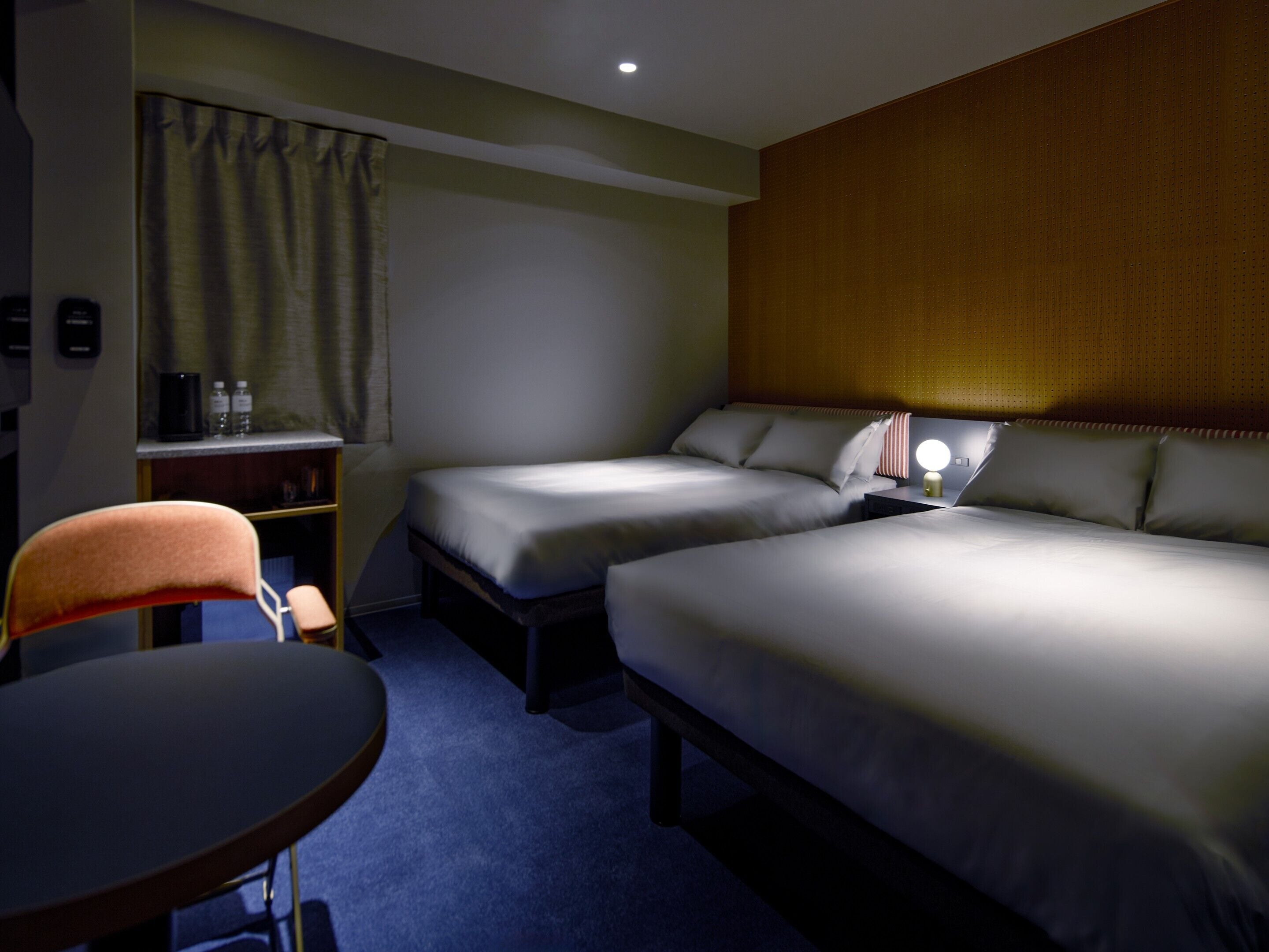 Una habitación de hotel con dos camas, un escritorio, una silla y una mesita.