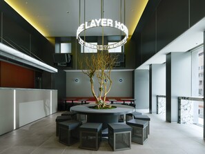 A modern hotel lobby with a central seating area, a decorative tree, and a neon sign reading 'LAYER HOTEL'. - BASE LAYER HOTEL Fukuoka (Fukuoka)