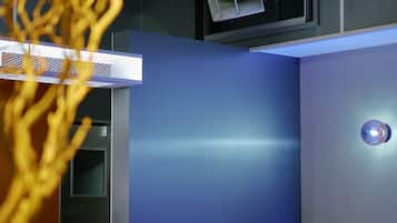 Un interior moderno con una pared azul, un respiradero en el techo y una lámpara.