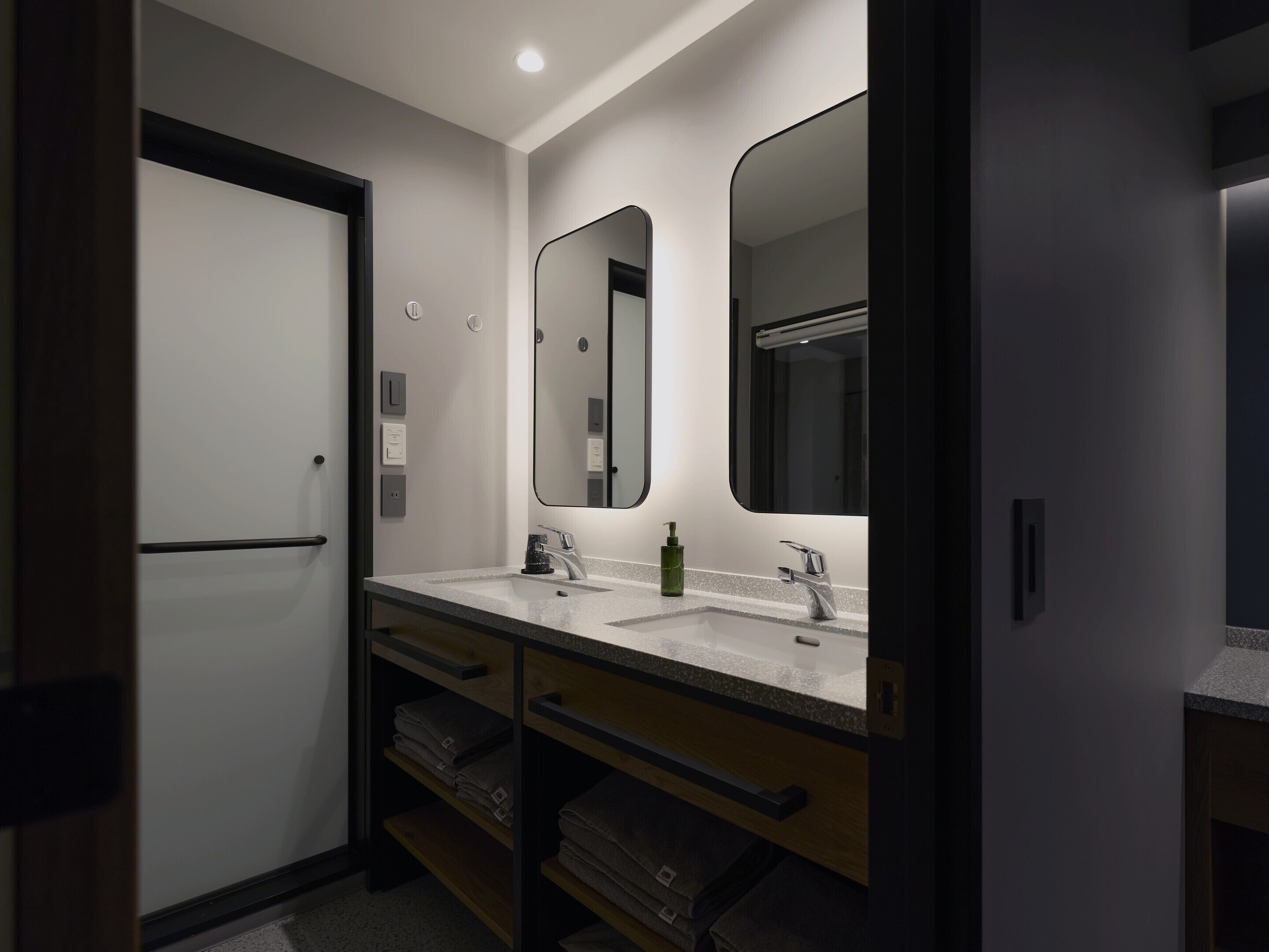 A modern bathroom with two sinks, a large mirror, and a towel rack.