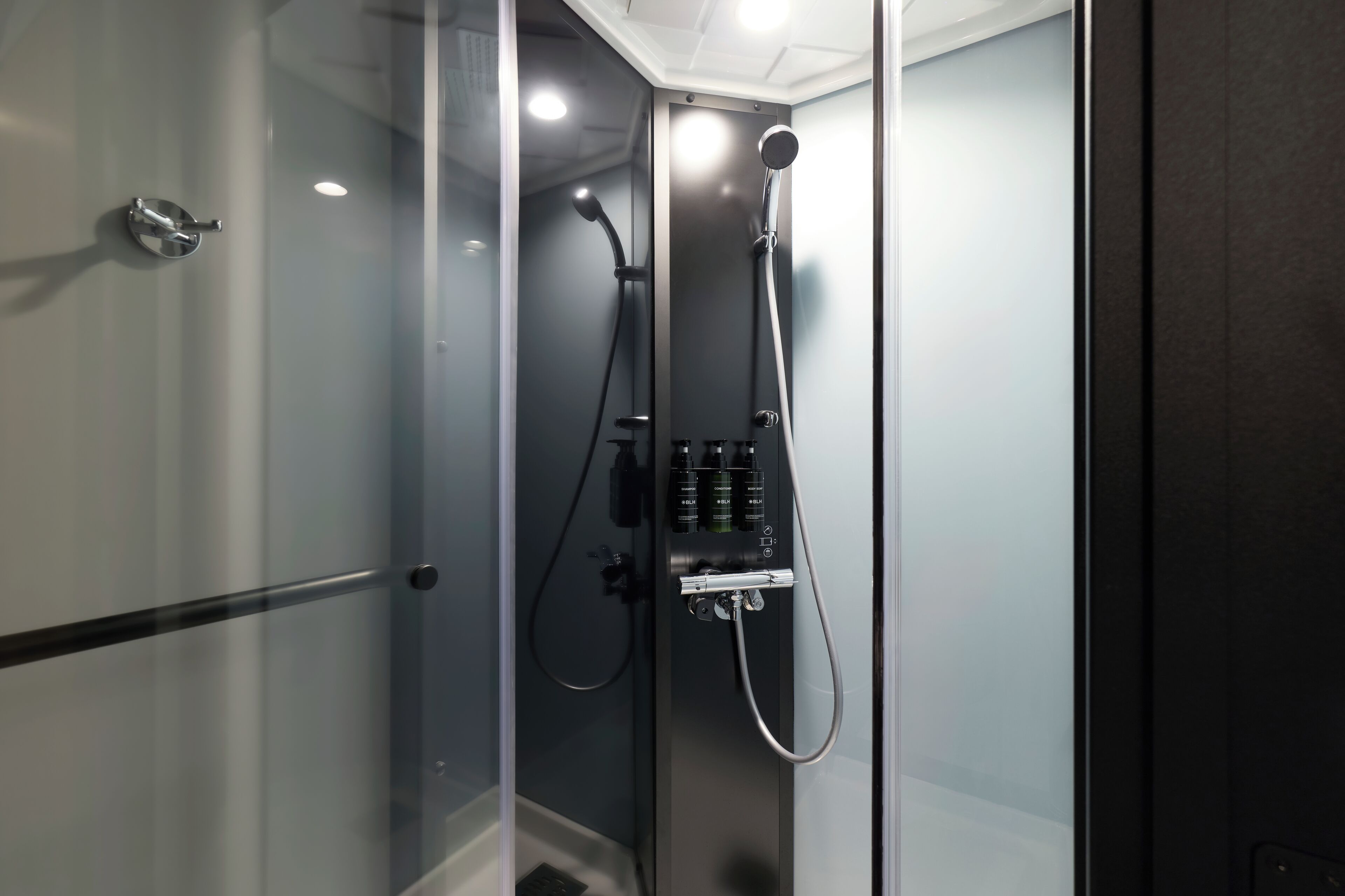 A modern shower with a control panel, glass doors, and a visible drain.