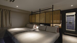 A hotel room with two beds, a window with a view, a bathroom with a shower, and a ceiling vent.