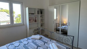 Ett sovrum med en säng, en garderob, ett skrivbord och ett fönster.