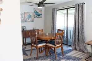 A dining area with a round table, wooden chairs, a ceiling fan, and a view through a glass door. - Resort Condo · Heated Pool w/ Slide · Near Beaches (Bradenton)