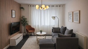 Un soggiorno moderno con una TV a schermo piatto, un divano, un tavolino da caffè e una lampada da terra.