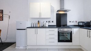 Una cucina moderna con mobili bianchi, forno integrato, microonde e cappa aspirante in acciaio inossidabile.