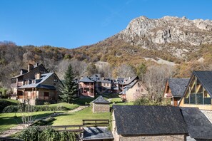 A cluster of stone buildings with multiple balconies, set against a backdrop of a rocky mountain.