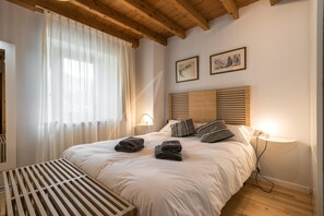 A neatly made bed with towels, a bedside lamp, and a wooden bench.