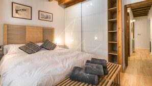 Een slaapkamer met een houten hoofdbord, wit beddengoed en een nachtkastje met handdoeken.