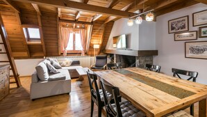 Een gezellig loft-appartement met houten plafond, een eettafel en een bank.