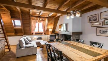 Een gezellig loft-appartement met houten plafond, een eettafel en een bank.