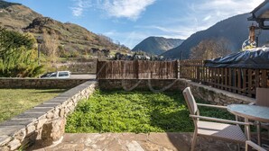 A stone pathway leading to a wooden deck with a chair and table, surrounded by greenery and a mountainous backdrop. - Casa Unhòla by SeaMount Rentals (Unha)