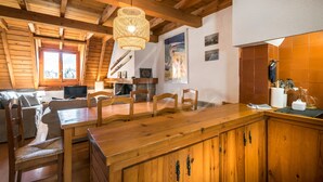 A wooden interior with a dining table, chairs, a hanging light fixture, and a fireplace. - Casa Unhòla by SeaMount Rentals (Unha)