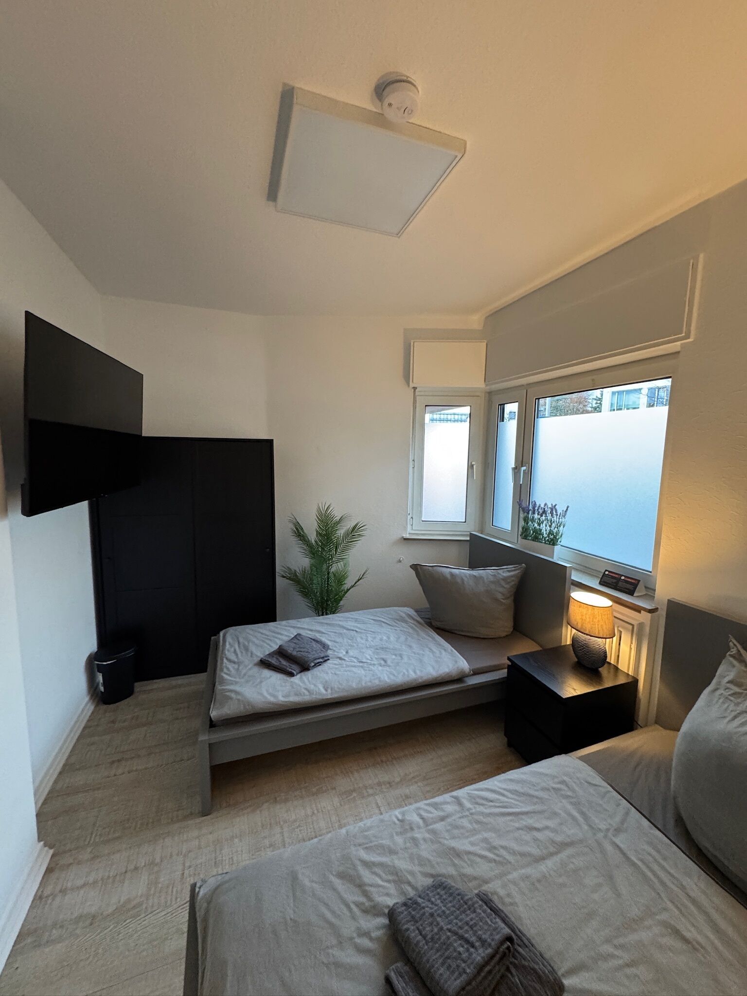 Une chambre à coucher moderne, avec un lit, une table de chevet, une lampe et un téléviseur fixé au mur.
