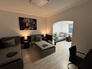 Een moderne slaapkamer met een bed, een bank, een bureau en een zithoekje.