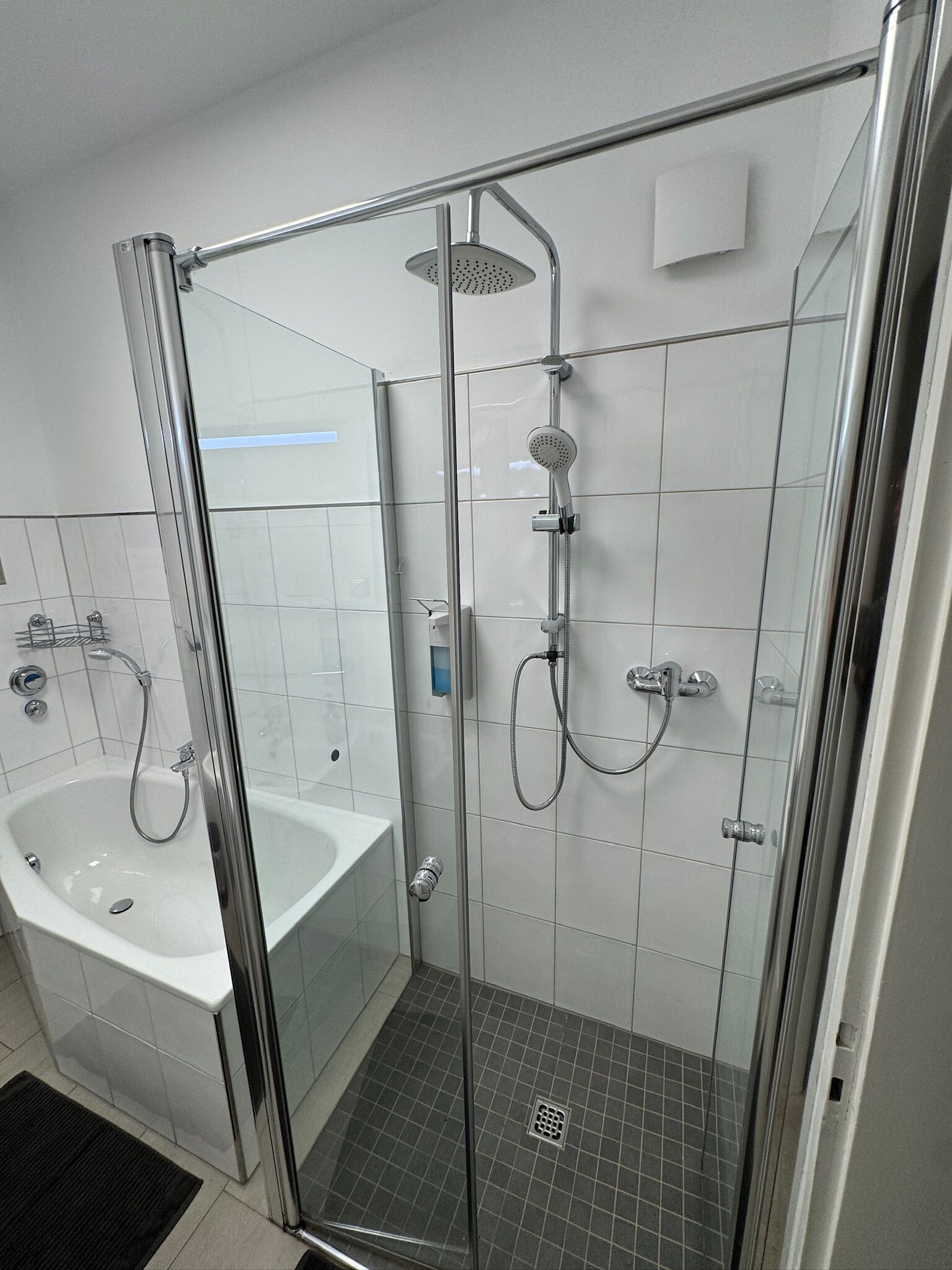 Ein modernes Badezimmer mit einer Duschkabine, einer freistehenden Badewanne und einem separaten Waschbereich.
