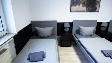 A twin room with two beds, a window, a painting, and bedside tables with lamps.