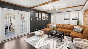 A modern living room with a sectional sofa, a coffee table, and a patterned rug. - 6BD/3.5BA Modern Rustic Retreat | Yard, Pool & BBQ (Richardson)