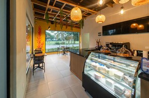 A cafe interior with a counter, display case, and hanging lights. - ONA | Terrace Picuzzi & Beach (Bavaro)
