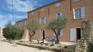 A building with multiple windows and doors, a gravel driveway, and a stone wall. - Château Turcan - Bastide 18th century 6 bdrms with swimming pool (Ansouis)