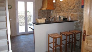 A kitchen with a stone wall, a wooden bar counter, and three wooden stools. - Château Turcan - Bastide 18th century 6 bdrms with swimming pool (Ansouis)