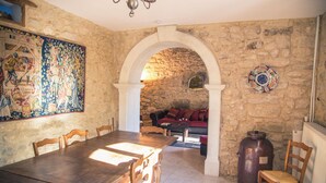 A stone-walled room with a dining table, chairs, a sofa, and a large vase. - Château Turcan - Bastide 18th century 6 bdrms with swimming pool (Ansouis)