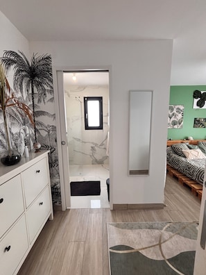 Ein modernes Schlafzimmer mit einem Bett, einem Schminktisch, einem Spiegel und einer Tür zu einem Badezimmer.