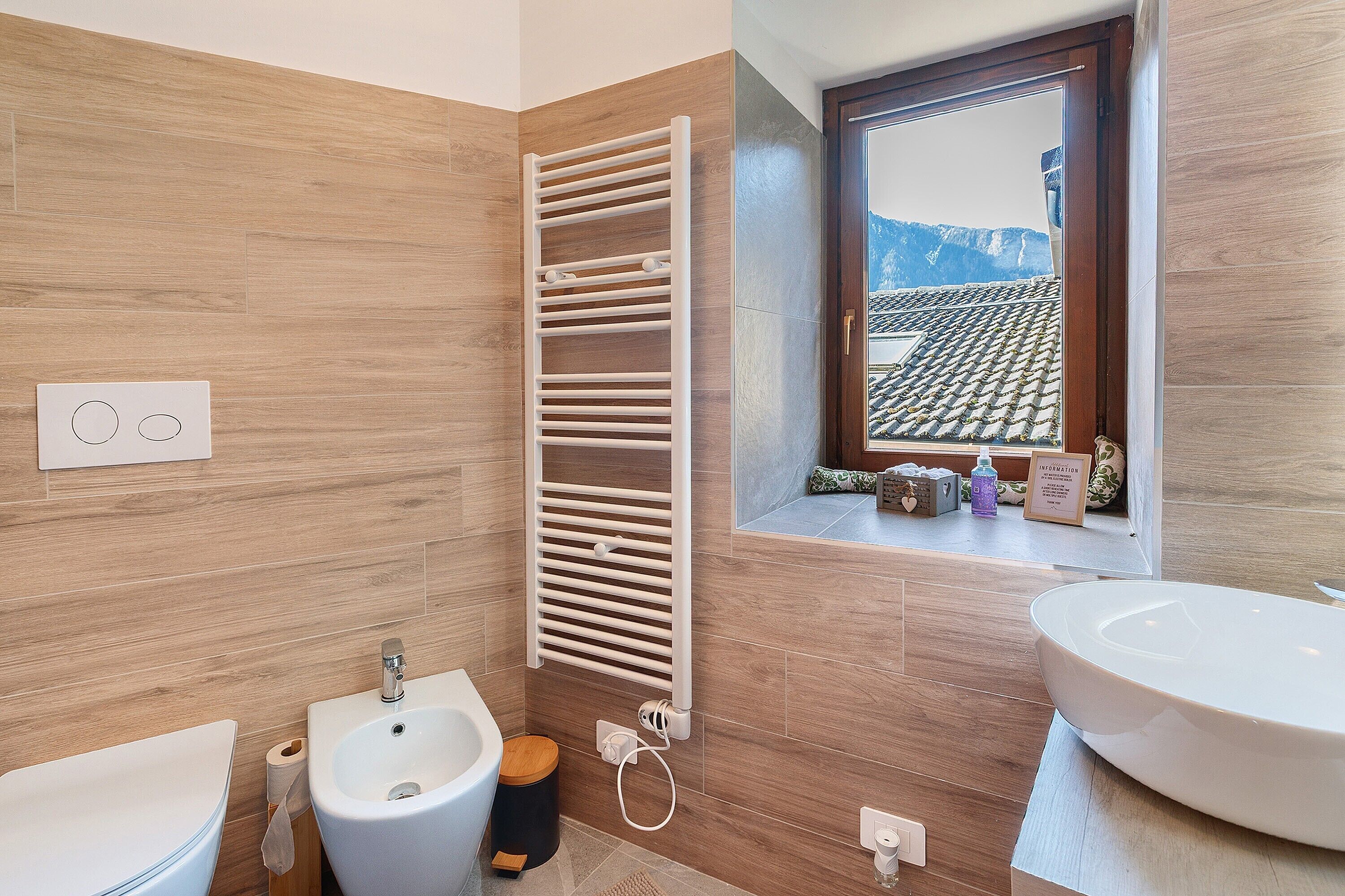 Une salle de bain moderne équipée d’un bidet, d’un lavabo, d’un porte-serviettes et d’une fenêtre donnant sur les montagnes.