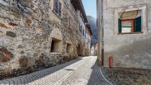 Eine enge Kopfsteinpflasterstraße, gesäumt von Steinbauten mit Rundbogenfenstern und einem roten Feuerhydrant.